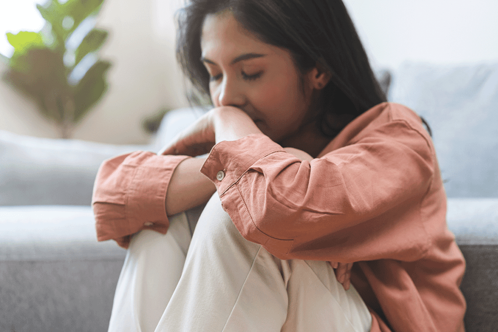 woman sits on the ground with her knees to her chest leaning on her arms and legs while struggling with alcohol and emotions